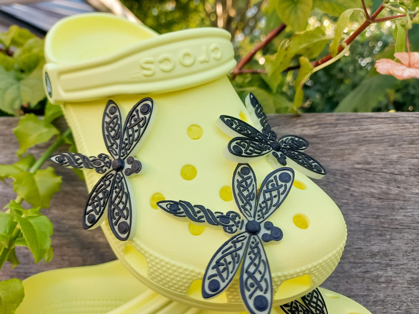 3D-printed glow-in-the-dark dragonfly charm with a Celtic weave pattern on a shoe shoe. The intricate design adds a whimsical and enchanting touch to the footwear, perfect for day or night style.