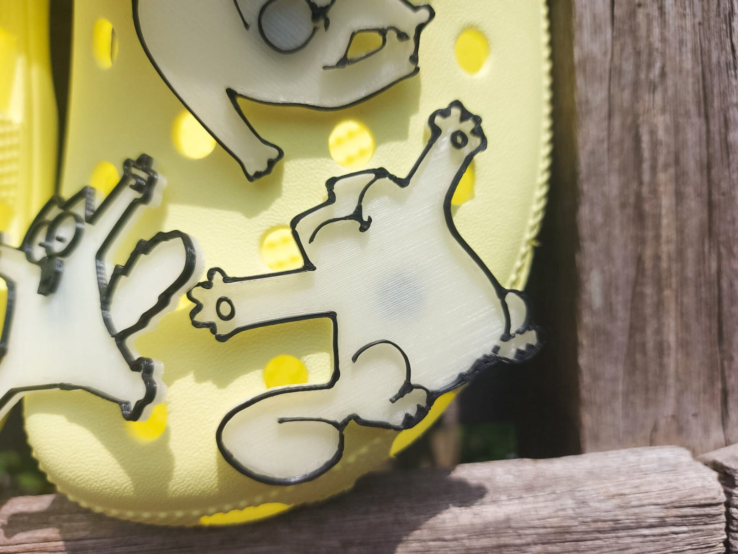 Various 3d-printed cartoon cat shoe charms that glow in the dark on a pair of yellow shoes. Each cat has unique features and expressions.