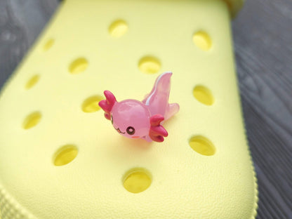 Colorful axolotl charms on a pair of yellow shoes shoes. The axolotls are blue, purple, green, orange, yellow and pink and have cute, smiling faces.