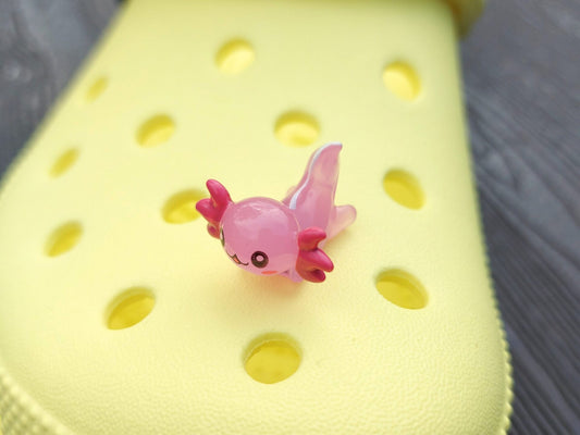 Colorful axolotl charms on a pair of yellow shoes shoes. The axolotls are blue, purple, green, orange, yellow and pink and have cute, smiling faces.
