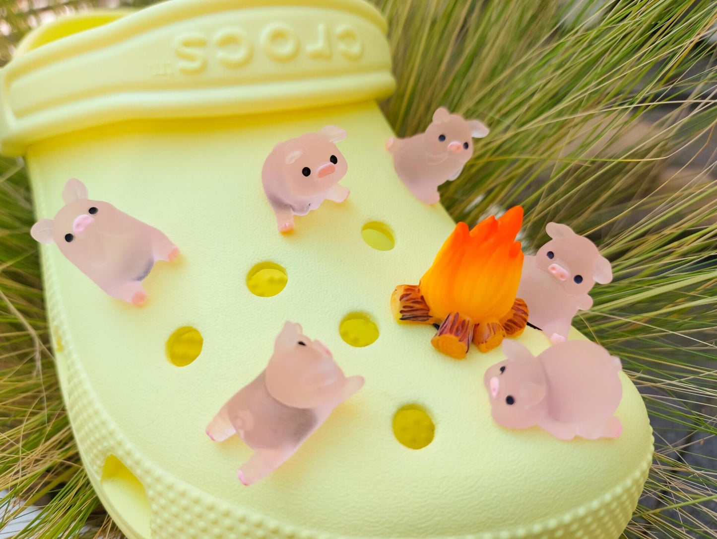 Set of glow-in-the-dark shoe charms featuring adorable pigs around a campfire on a shoe shoe. These playful accessories light up in the dark, adding a unique and whimsical touch to your footwear, perfect for personalizing your shoes.