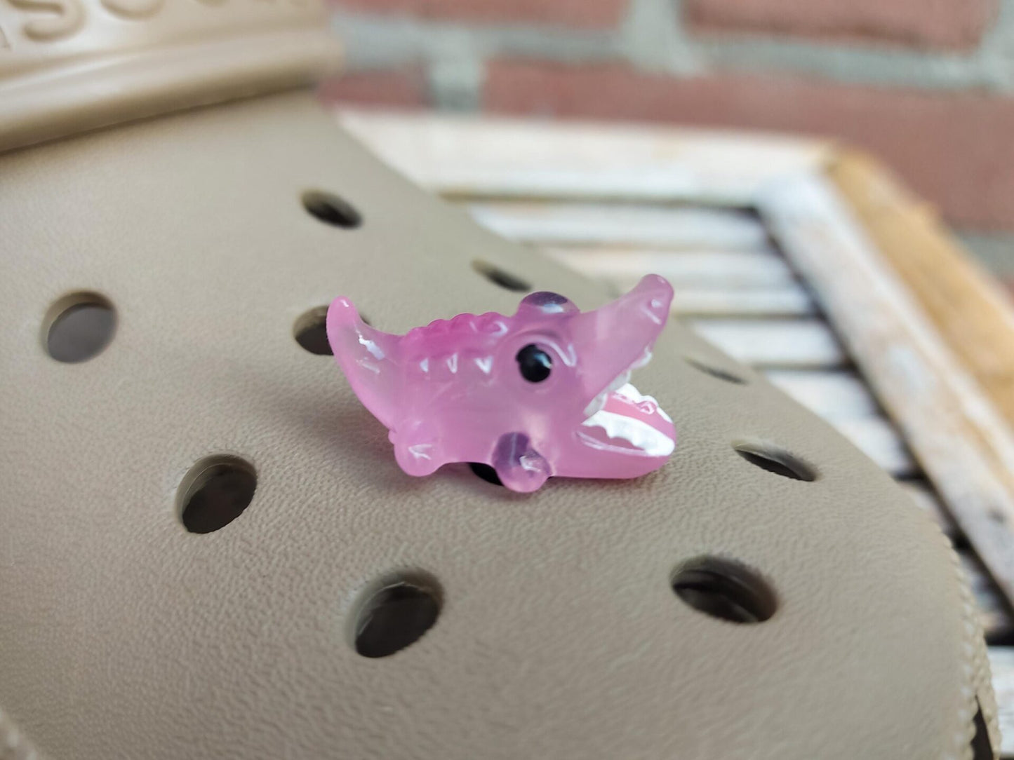 A set of glow-in-the-dark shoeodile charms adorns a shoes shoe. Each charm is shaped like a small, detailed shoeodile, appearing in a range of bright colors that glow vividly in the dark.