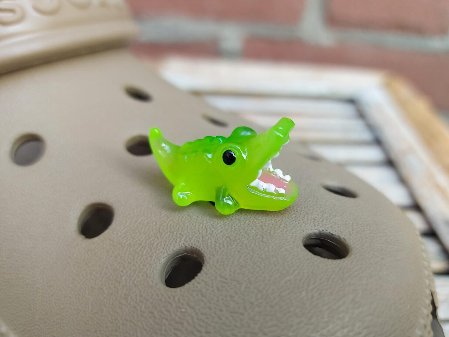 A set of glow-in-the-dark shoeodile charms adorns a shoes shoe. Each charm is shaped like a small, detailed shoeodile, appearing in a range of bright colors that glow vividly in the dark.