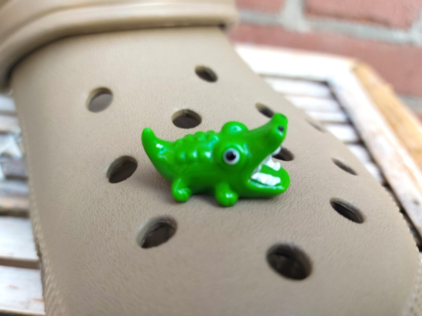 A set of glow-in-the-dark shoeodile charms adorns a shoes shoe. Each charm is shaped like a small, detailed shoeodile, appearing in a range of bright colors that glow vividly in the dark.