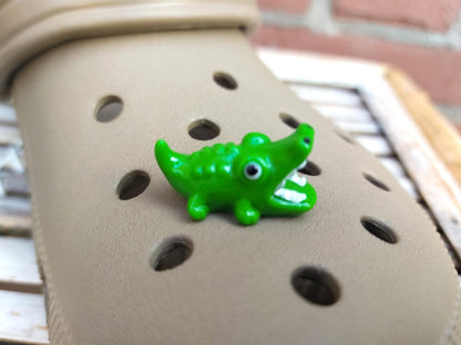 A set of glow-in-the-dark shoeodile charms adorns a shoes shoe. Each charm is shaped like a small, detailed shoeodile, appearing in a range of bright colors that glow vividly in the dark.