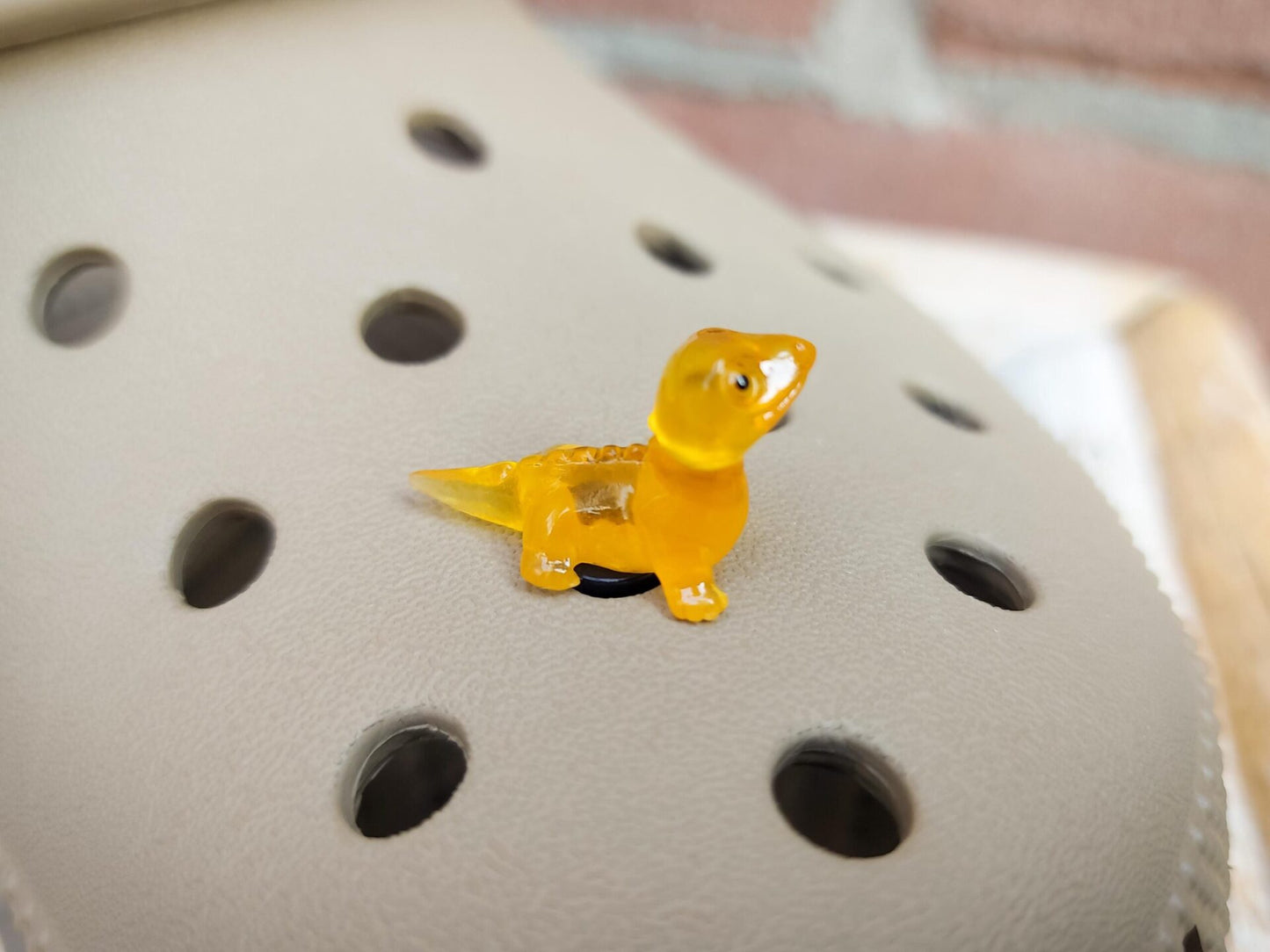 A set of vibrant glow-in-the-dark lizard charms attached to a pair of shoes, featuring tiny, detailed geckos in various colors. These charms, glowing softly in low light, bring a playful and adventurous vibe, perfect for adding a wild touch.