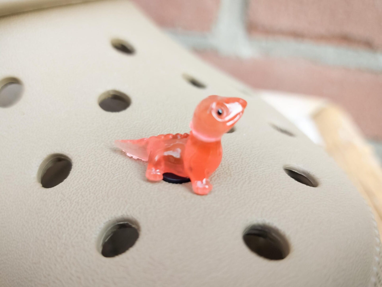 A set of vibrant glow-in-the-dark lizard charms attached to a pair of shoes, featuring tiny, detailed geckos in various colors. These charms, glowing softly in low light, bring a playful and adventurous vibe, perfect for adding a wild touch.