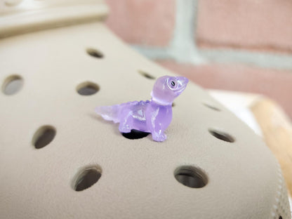 A set of vibrant glow-in-the-dark lizard charms attached to a pair of shoes, featuring tiny, detailed geckos in various colors. These charms, glowing softly in low light, bring a playful and adventurous vibe, perfect for adding a wild touch.