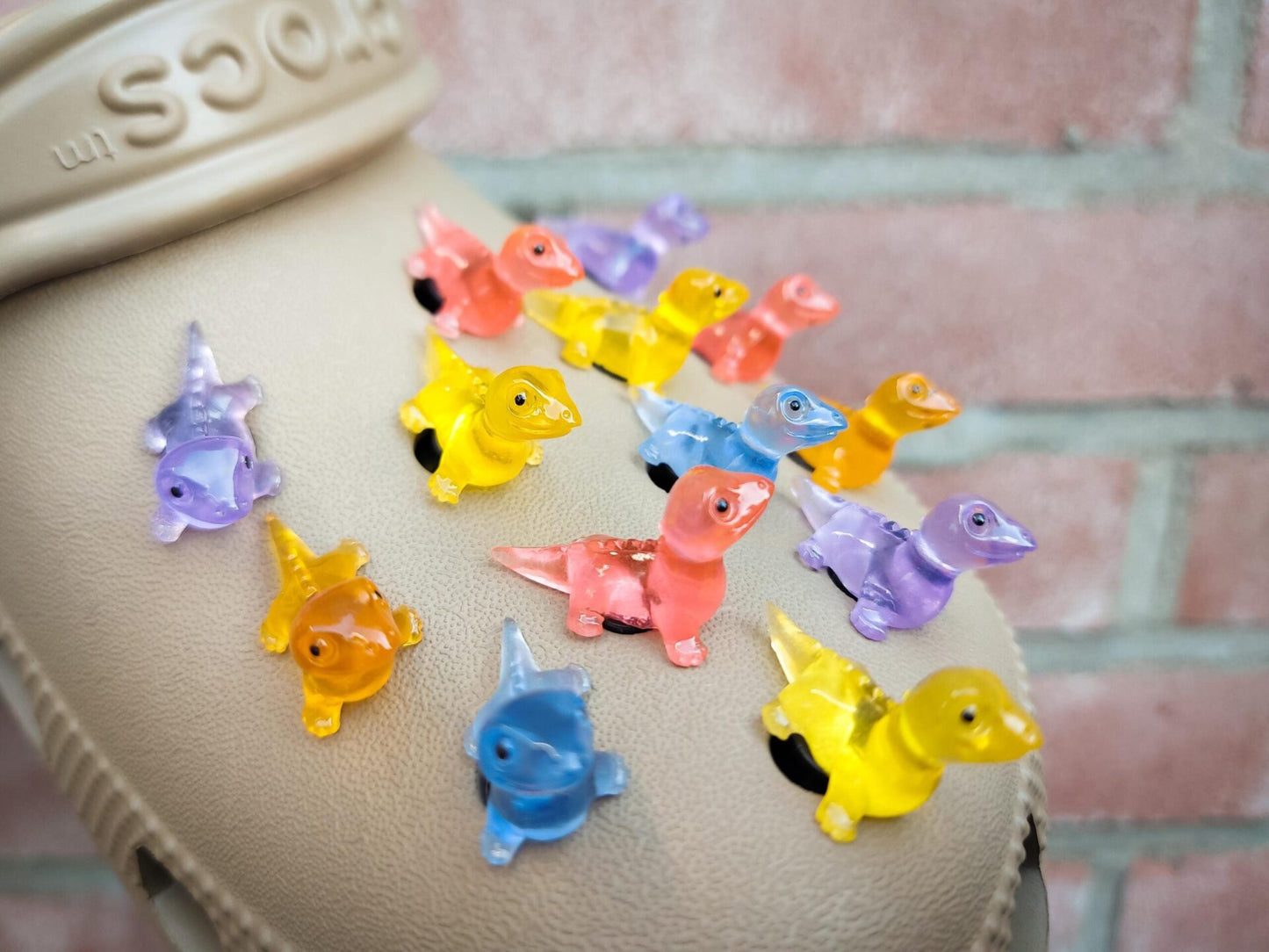 A set of vibrant glow-in-the-dark lizard charms attached to a pair of shoes, featuring tiny, detailed geckos in various colors. These charms, glowing softly in low light, bring a playful and adventurous vibe, perfect for adding a wild touch.