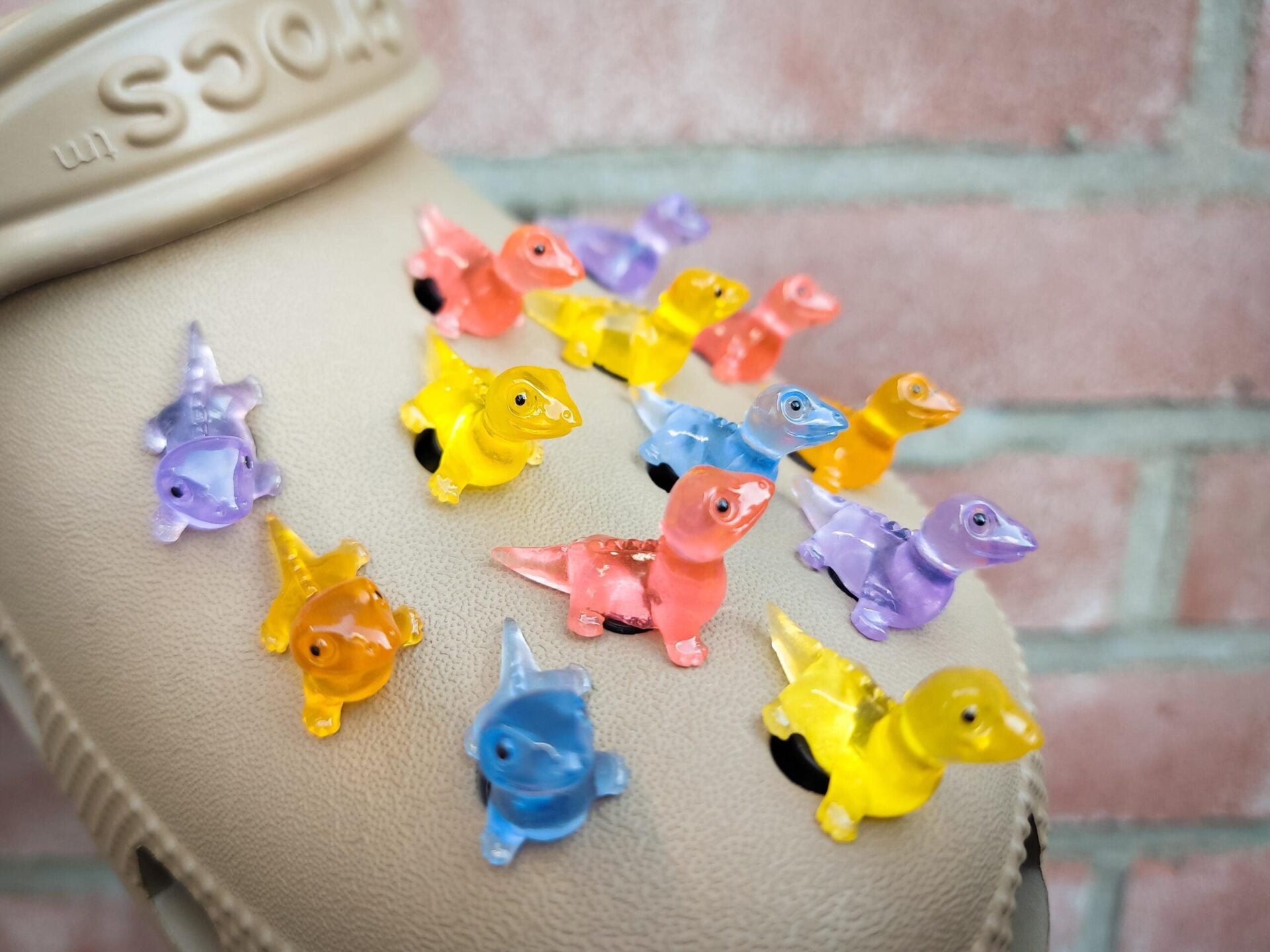 A set of vibrant glow-in-the-dark lizard charms attached to a pair of shoes, featuring tiny, detailed geckos in various colors. These charms, glowing softly in low light, bring a playful and adventurous vibe, perfect for adding a wild touch.
