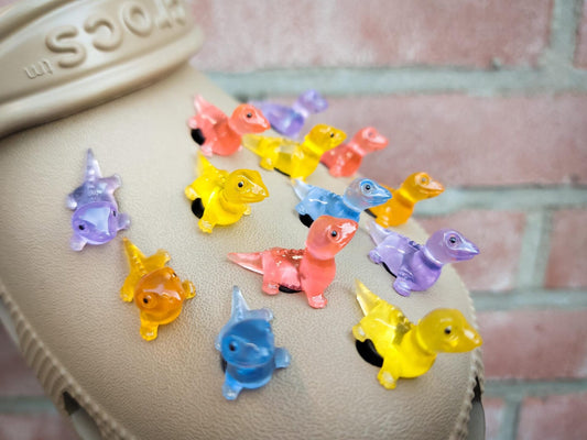 A set of vibrant glow-in-the-dark lizard charms attached to a pair of shoes, featuring tiny, detailed geckos in various colors. These charms, glowing softly in low light, bring a playful and adventurous vibe, perfect for adding a wild touch.
