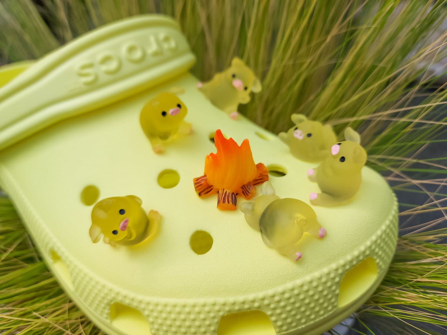 Set of glow-in-the-dark shoe charms featuring adorable pigs around a campfire on a shoe shoe. These playful accessories light up in the dark, adding a unique and whimsical touch to your footwear, perfect for personalizing your shoes.