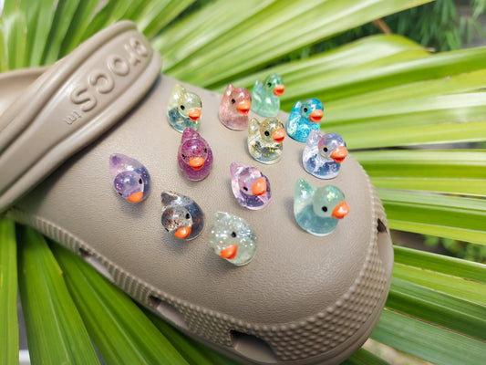 Close-up of glitter duck charms on a shoe shoe, featuring sparkling, glitter-coated duck designs. The charms are securely attached, adding a fun and eye-catching shimmer to the shoe with a playful, vibrant look."