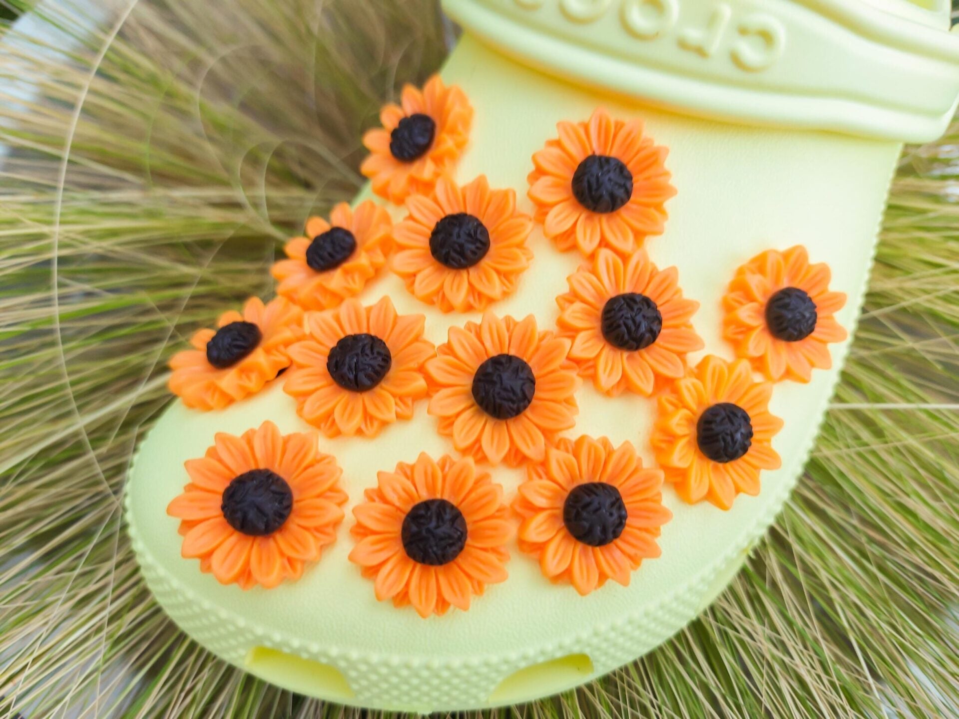 Sunflower charms on a pair of yellow shoes shoes. This floral charm has a vibrant orange-yellow color, perfect for the spring and summer time.