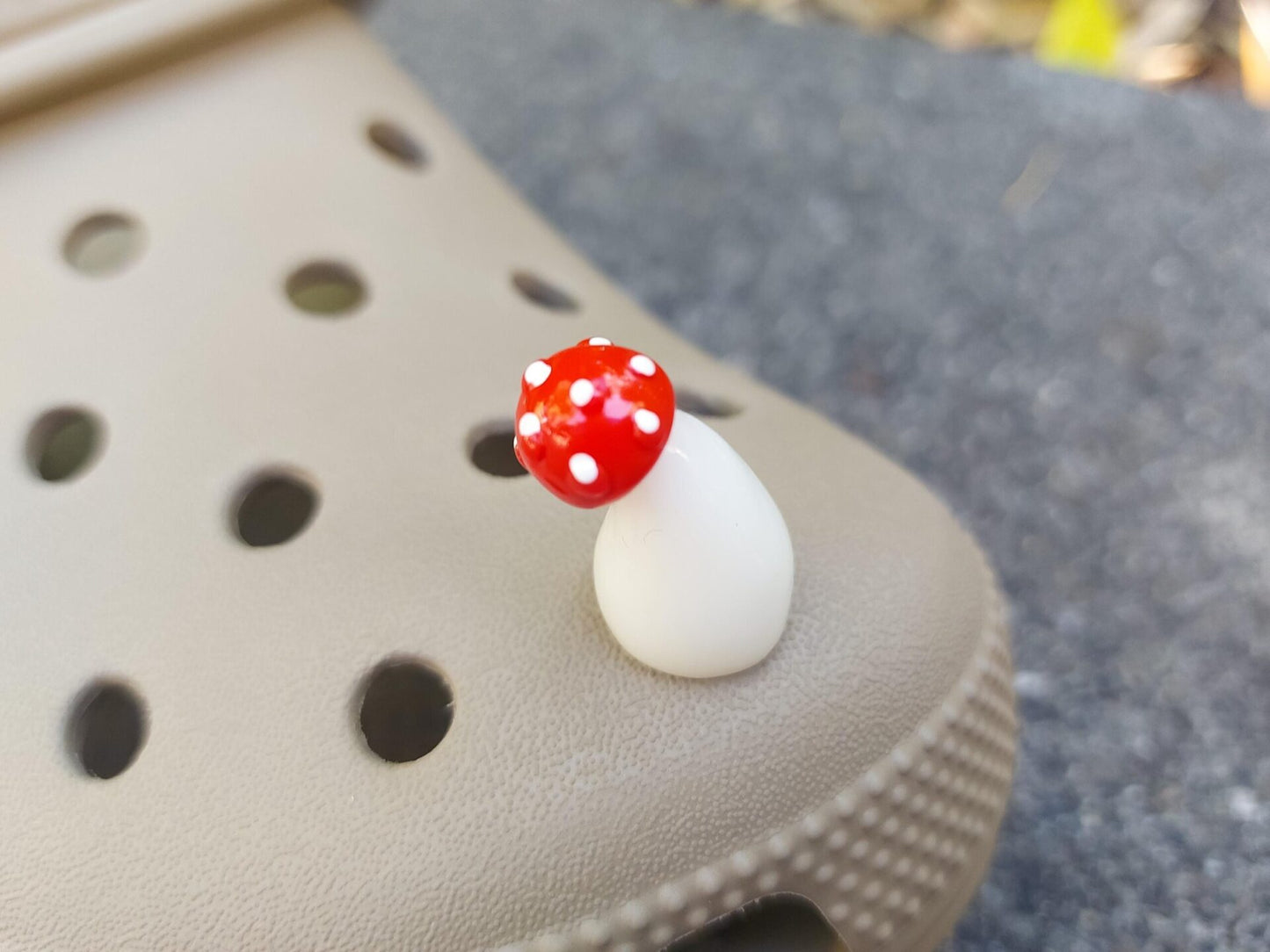 Glow in the dark forest mushroom shoe charms with white stems and red caps with white dots on a pair of shoes shoes.