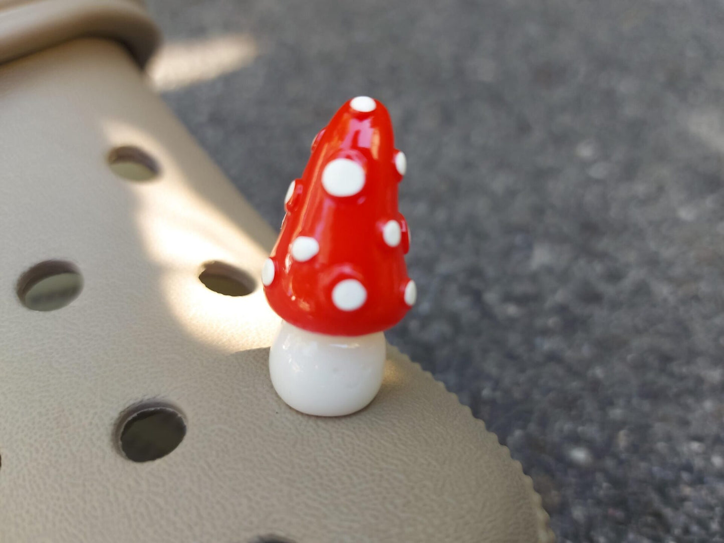 Glow in the dark forest mushroom shoe charms with white stems and red caps with white dots on a pair of shoes shoes.
