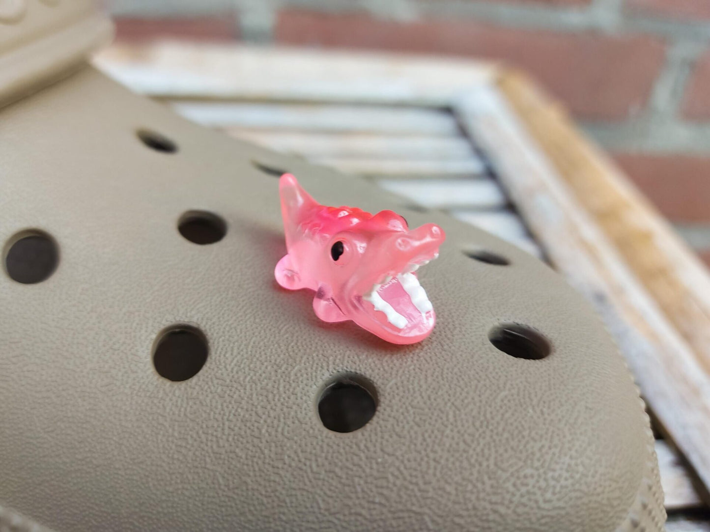 A set of glow-in-the-dark shoeodile charms adorns a shoes shoe. Each charm is shaped like a small, detailed shoeodile, appearing in a range of bright colors that glow vividly in the dark.