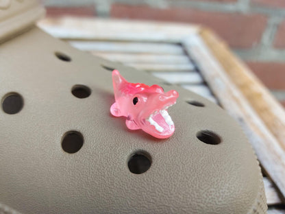 A set of glow-in-the-dark shoeodile charms adorns a shoes shoe. Each charm is shaped like a small, detailed shoeodile, appearing in a range of bright colors that glow vividly in the dark.
