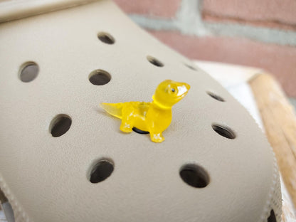A set of vibrant glow-in-the-dark lizard charms attached to a pair of shoes, featuring tiny, detailed geckos in various colors. These charms, glowing softly in low light, bring a playful and adventurous vibe, perfect for adding a wild touch.