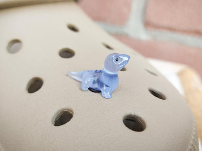 A set of vibrant glow-in-the-dark lizard charms attached to a pair of shoes, featuring tiny, detailed geckos in various colors. These charms, glowing softly in low light, bring a playful and adventurous vibe, perfect for adding a wild touch.