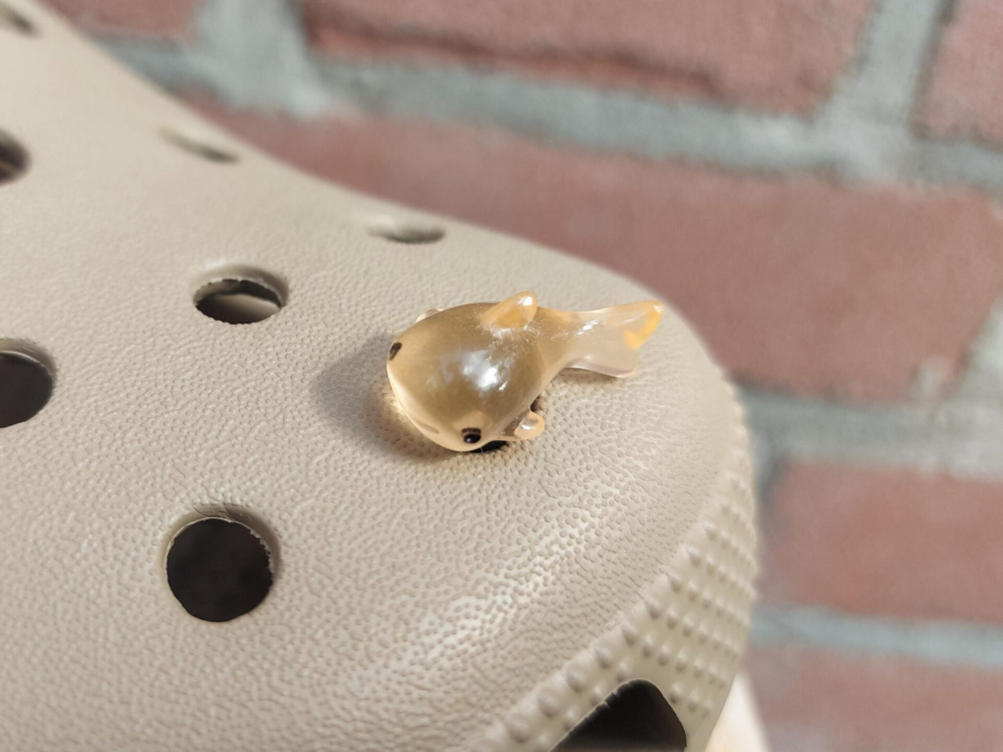 Close-up of glow-in-the-dark shark charms on a shoe shoe, showcasing their detailed design and soft, glowing effect. The sharks are securely attached, and their luminous feature adds a fun, ocean-inspired touch to the shoe in a dark setting.