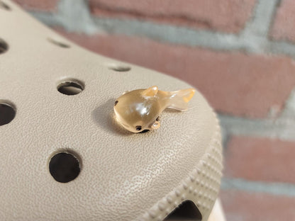 Close-up of glow-in-the-dark shark charms on a shoe shoe, showcasing their detailed design and soft, glowing effect. The sharks are securely attached, and their luminous feature adds a fun, ocean-inspired touch to the shoe in a dark setting.