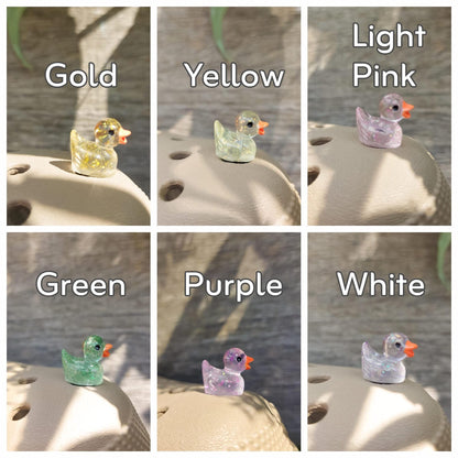 Close-up of glitter duck charms on a shoe shoe, featuring sparkling, glitter-coated duck designs. The charms are securely attached, adding a fun and eye-catching shimmer to the shoe with a playful, vibrant look."