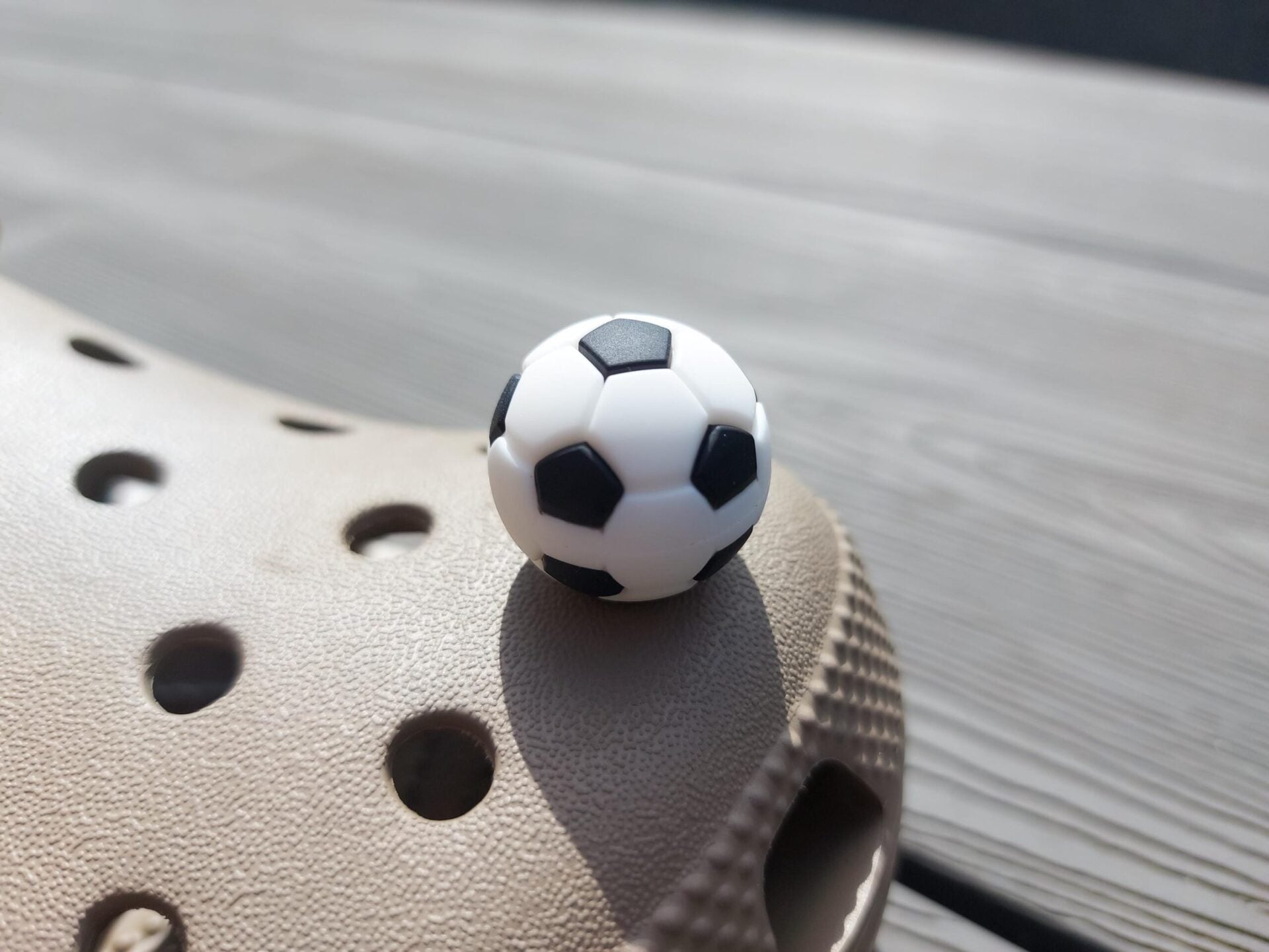 Close-up of a set of 7 sports-themed charms on a shoe shoe, featuring a basketball, football, soccer ball, tennis ball, baseball, volleyball, and golf ball. The charms are securely attached, adding a fun, athletic touch to the shoe.