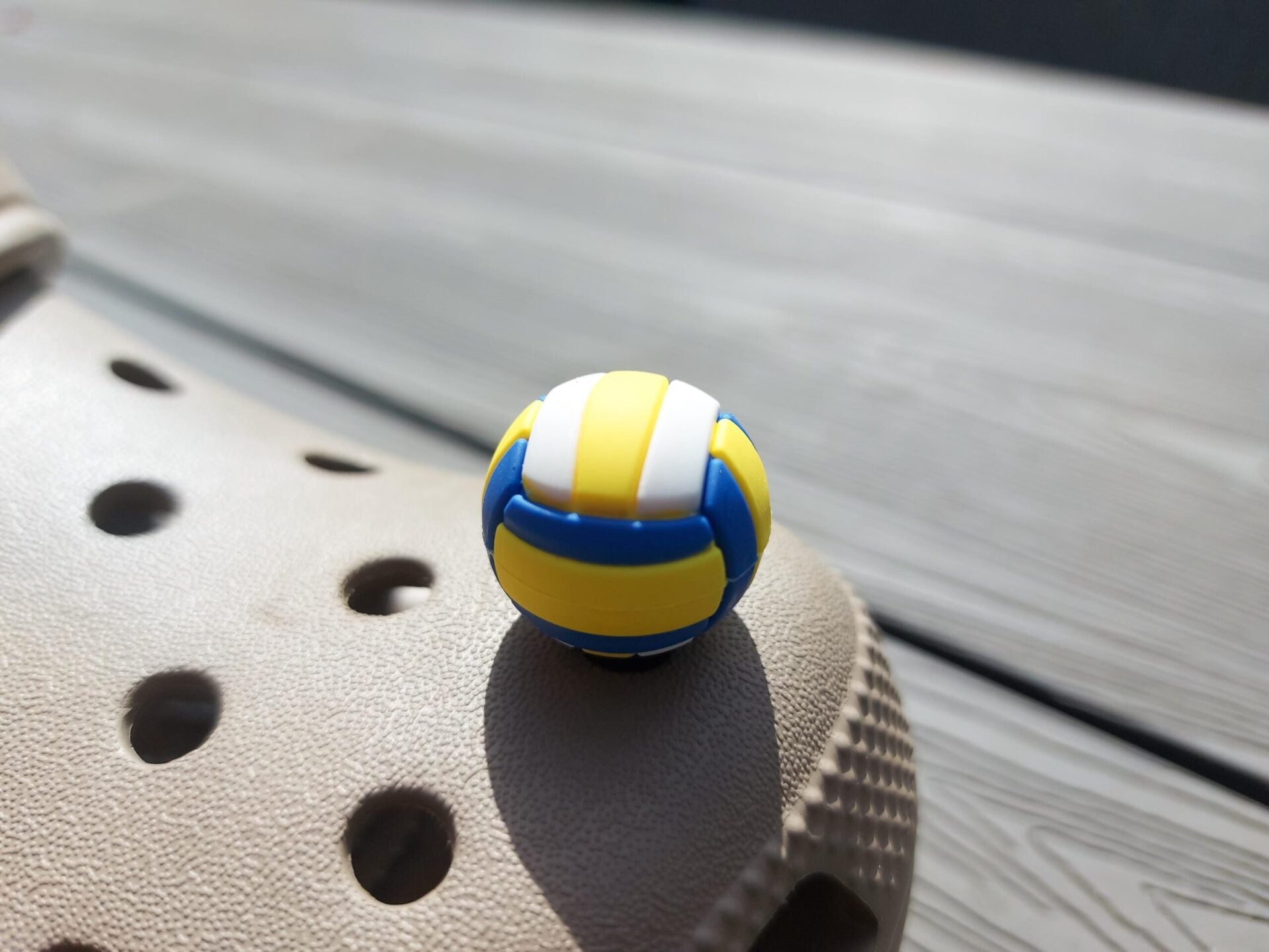Close-up of a set of 7 sports-themed charms on a shoe shoe, featuring a basketball, football, soccer ball, tennis ball, baseball, volleyball, and golf ball. The charms are securely attached, adding a fun, athletic touch to the shoe.