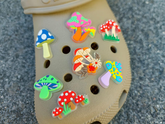 Close-up of beige shoes featuring glow-in-the-dark neon mushroom charms in vibrant colors like green, pink, and orange. The luminous mushrooms stand out against the shoes, creating a playful and eye-catching effect.
