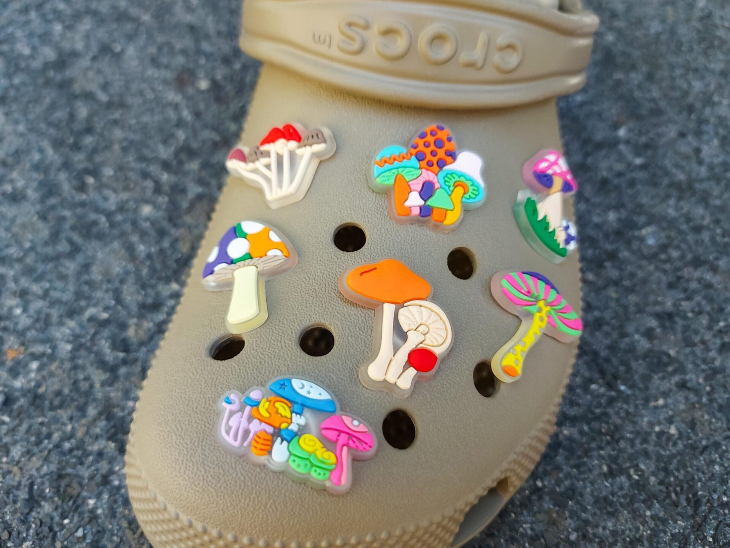 Close-up of beige shoes featuring glow-in-the-dark neon mushroom charms in vibrant colors like green, pink, and orange. The luminous mushrooms stand out against the shoes, creating a playful and eye-catching effect.