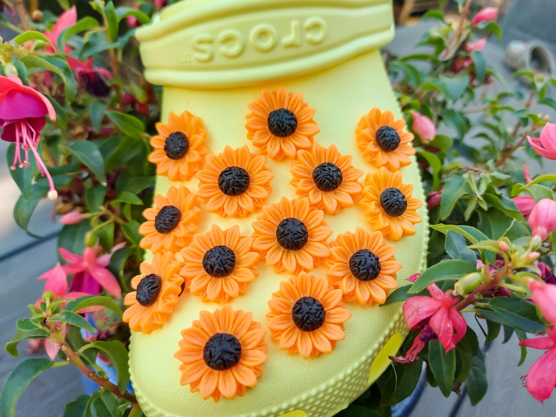 Sunflower charms on a pair of yellow shoes shoes. This floral charm has a vibrant orange-yellow color, perfect for the spring and summer time.
