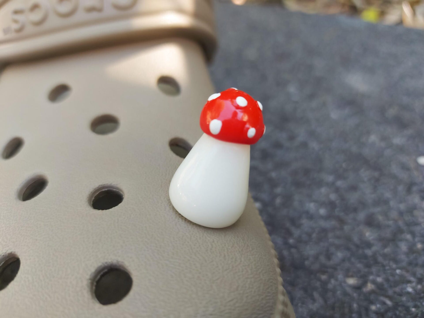 Glow in the dark forest mushroom shoe charms with white stems and red caps with white dots on a pair of shoes shoes.