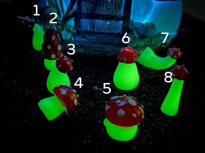Glow in the dark forest mushroom shoe charms with white stems and red caps with white dots on a pair of shoes shoes.