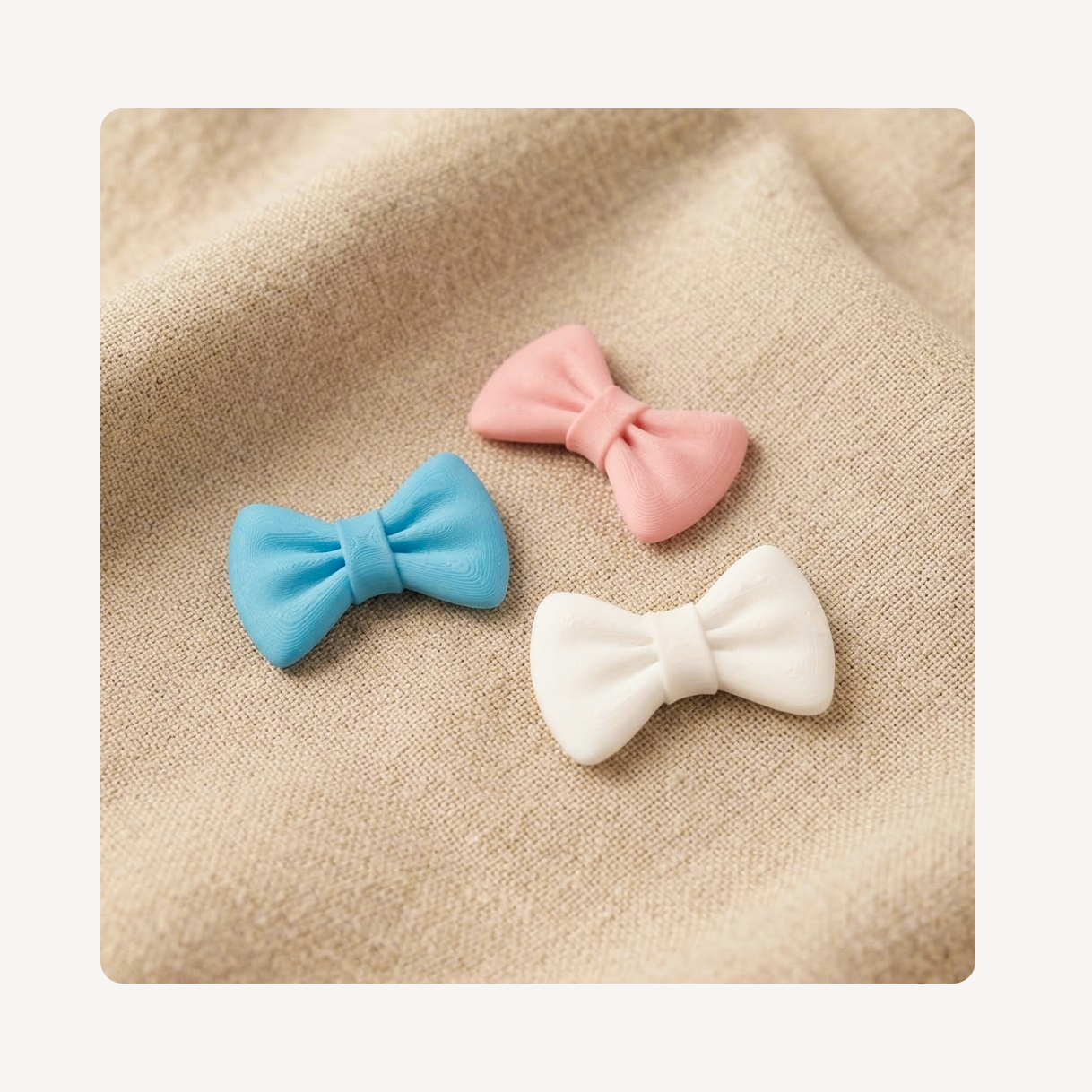 Three small bow tie-shaped clog charms in a textured plastic material, centered on a beige woven surface.