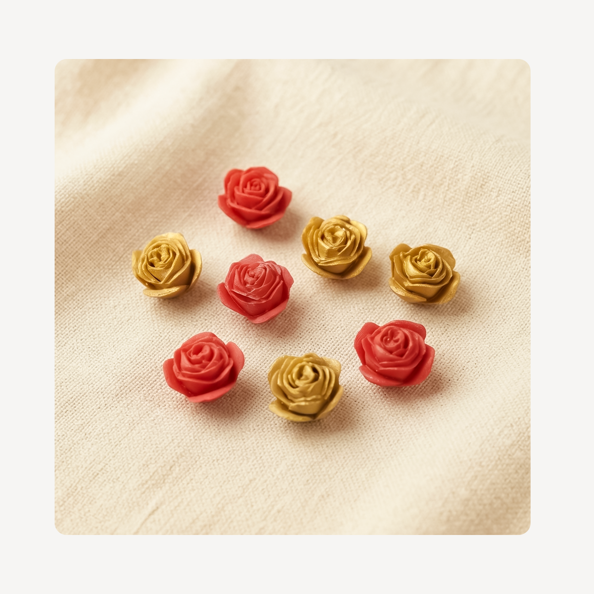Eight small rose-shaped decorative clog charms in alternating red and metallic gold, arranged on a light beige textured fabric background.