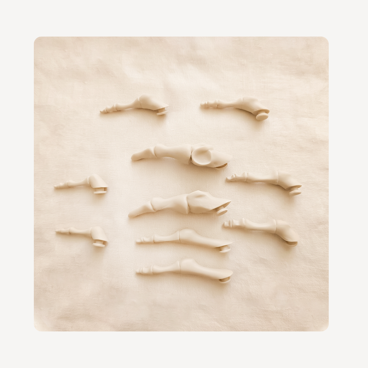 A set of miniature beige plastic bones or skeletal parts arranged on a textured beige background.