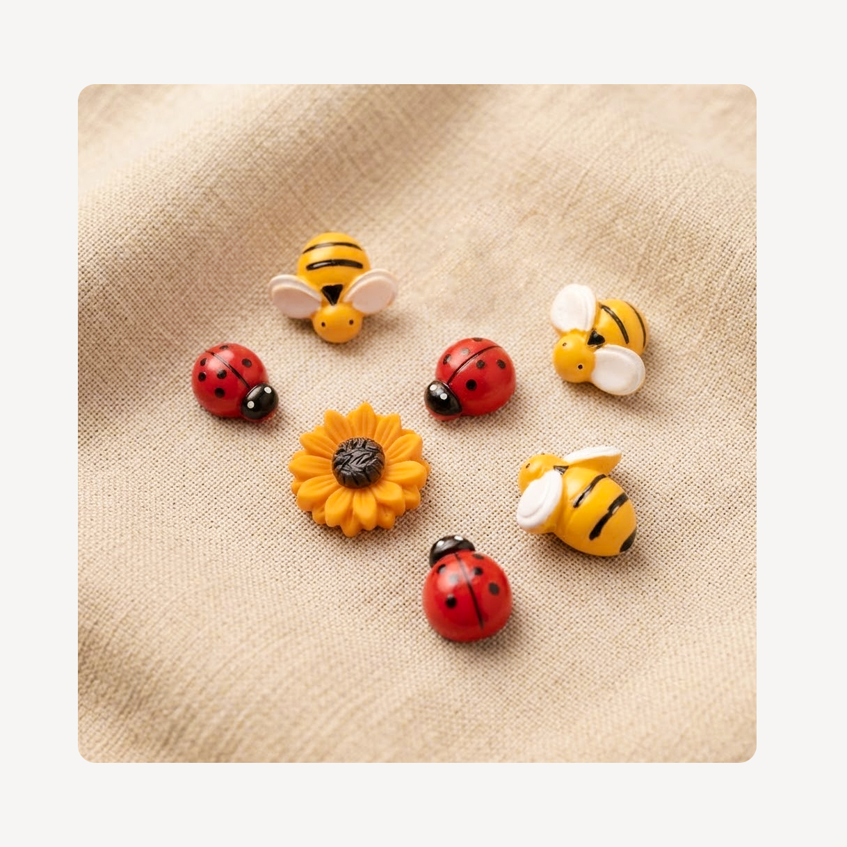 A set of colorful bee, ladybug, and sunflower clog charms arranged on a textured beige fabric background.