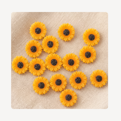 Ten small yellow sunflower-shaped clog charms with dark brown centers scattered on a textured beige fabric background.