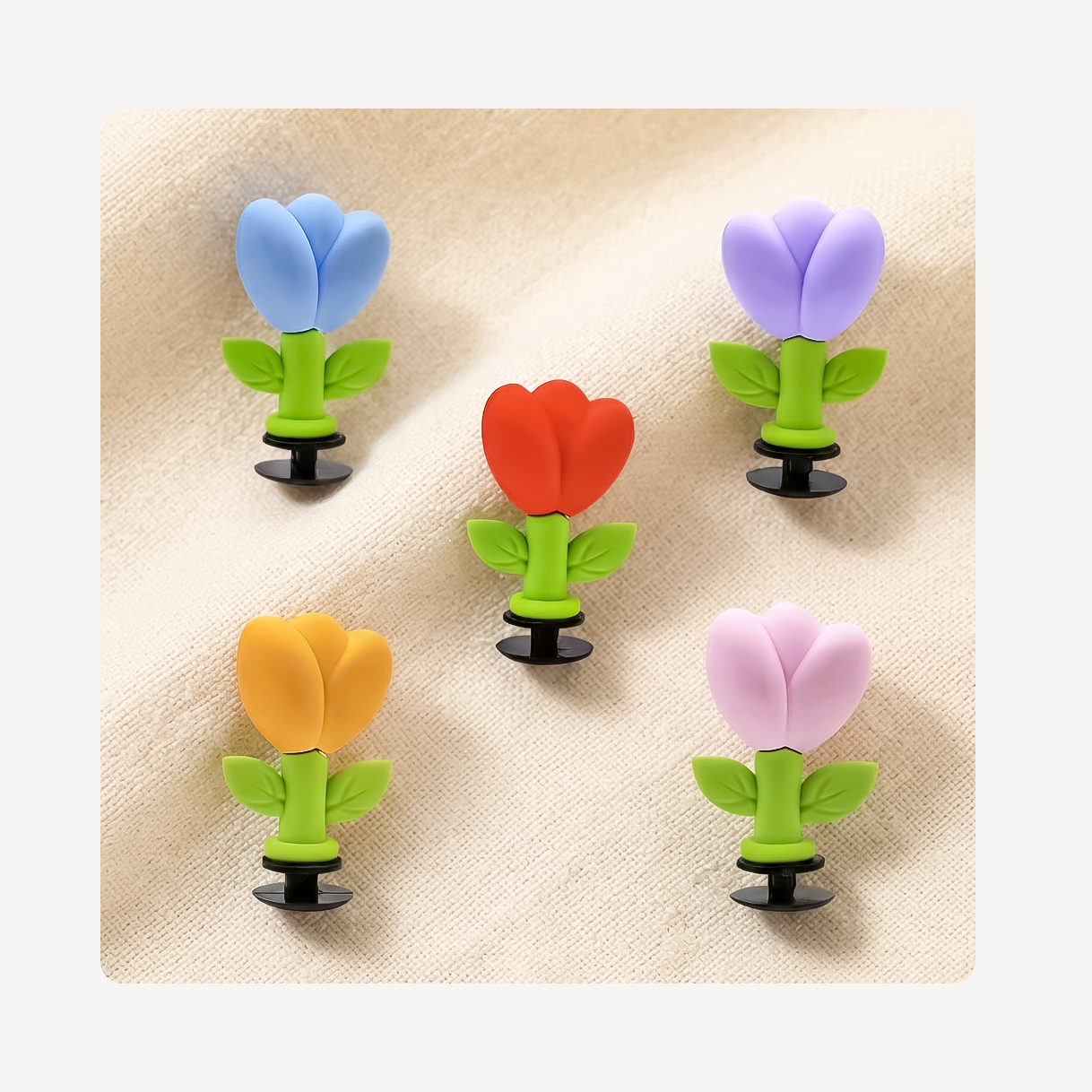 Five tulip flower clog charms arranged on a beige fabric background.