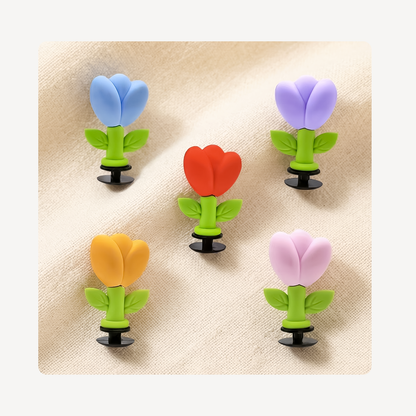 Five tulip flower clog charms arranged on a beige fabric background.