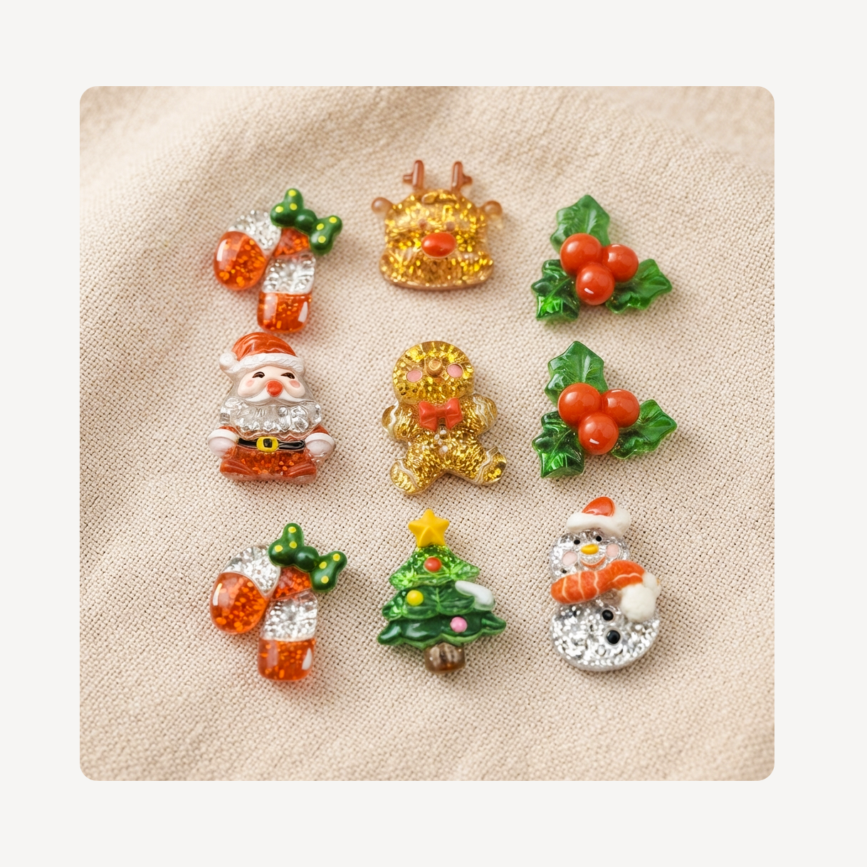Nine Christmas-themed clog charms arranged on a beige textured fabric background. The designs include a Santa Claus, a reindeer, holly with red berries, a gingerbread man, a snowman, a Christmas tree, and candy canes in gold, silver, and orange tones.