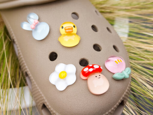 Close-up of a shoe decorated with a 5-piece jelly charm set, including two flowers, a yellow duck, a bunny with a pink bow, and a red mushroom. Each charm has a cute, soft, jelly-like appearance, adding a fun and playful vibe to the footwear.