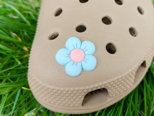 A cluster of vibrant cosmos flower charms decorates a Crocs shoe, with each charm showcasing delicate petals in shades of pink, white, and purple. The intricate details of the flowers mimic real cosmos blooms, with soft gradients and textured centers