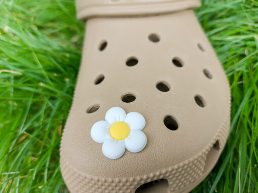 A cluster of vibrant cosmos flower charms decorates a Crocs shoe, with each charm showcasing delicate petals in shades of pink, white, and purple. The intricate details of the flowers mimic real cosmos blooms, with soft gradients and textured centers
