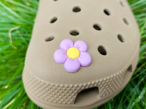 A cluster of vibrant cosmos flower charms decorates a Crocs shoe, with each charm showcasing delicate petals in shades of pink, white, and purple. The intricate details of the flowers mimic real cosmos blooms, with soft gradients and textured centers