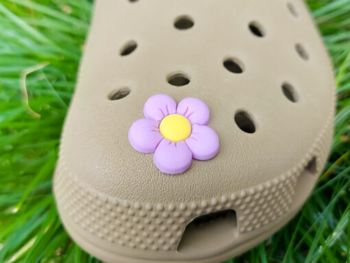 A cluster of vibrant cosmos flower charms decorates a Crocs shoe, with each charm showcasing delicate petals in shades of pink, white, and purple. The intricate details of the flowers mimic real cosmos blooms, with soft gradients and textured centers