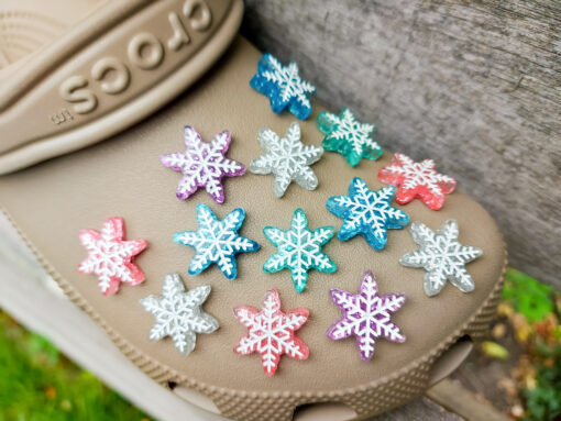 Colorful winter snowflake christmas shoe charms on a pair of Crocs shoes. The snowflakes are in multiple colors and have a sparkly glitter.