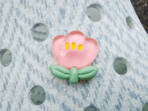 Close-up of a shoe decorated with a 5-piece jelly charm set, including two flowers, a yellow duck, a bunny with a pink bow, and a red mushroom. Each charm has a cute, soft, jelly-like appearance, adding a fun and playful vibe to the footwear.