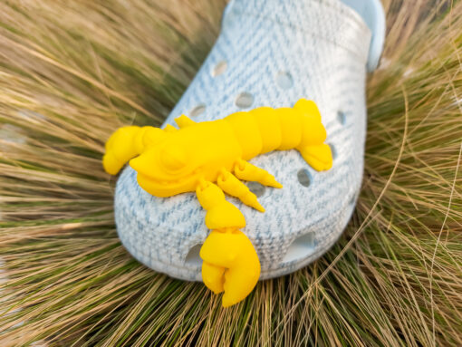 Colorful 3D printed flexi lobster charms in green, orange, yellow, and red, attached to Crocs shoes. Each lobster has a segmented, flexible body and realistic details, adding a playful marine-inspired style to the shoes.